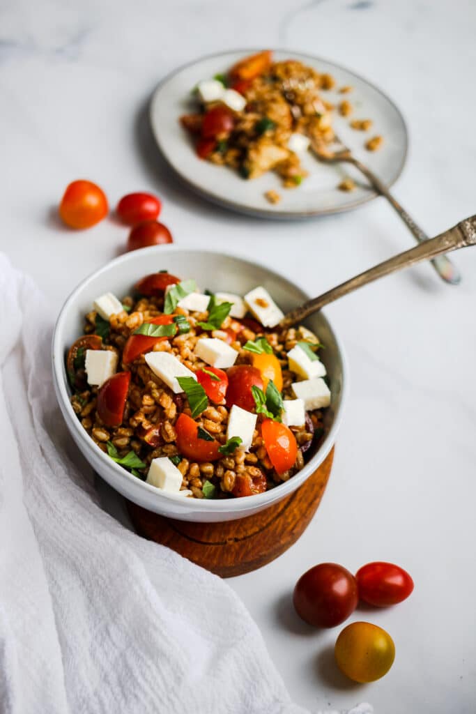 Bowl of grain salad with cheese and tomatoes.