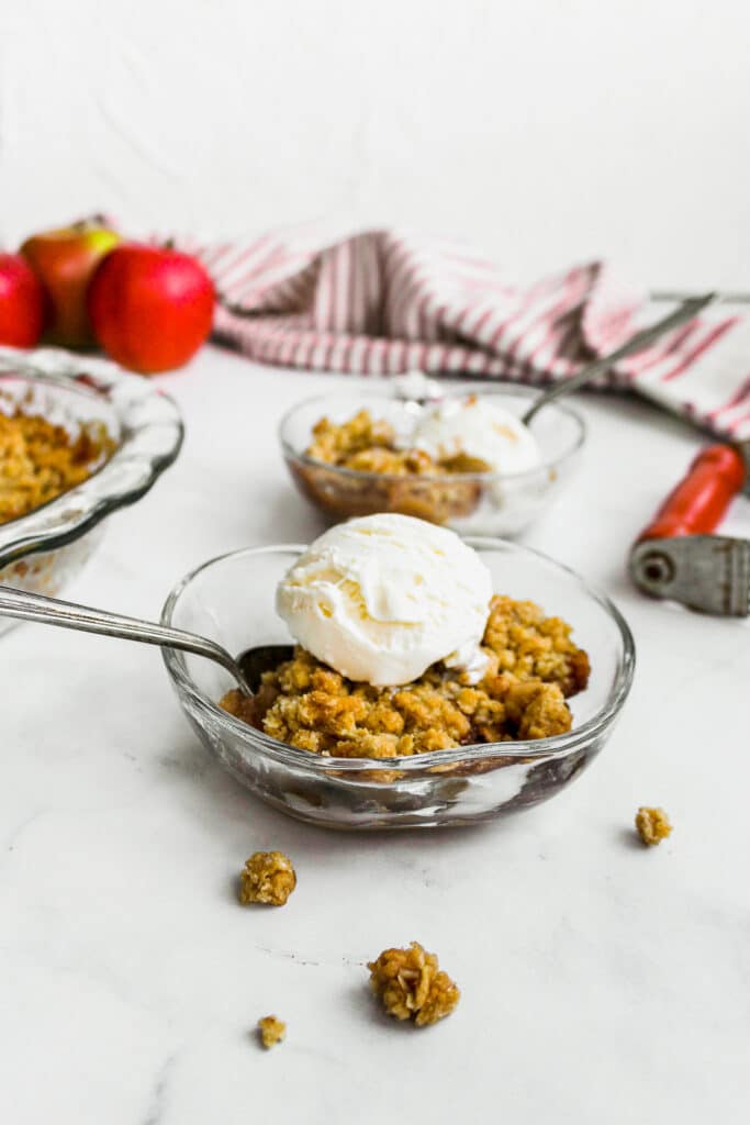 Delicious bowl of apple crisp with ice cream on top.