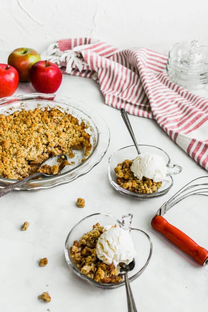 Apple crisp with oatmeal topping in apple shaped bowls with vanilla ice cream.