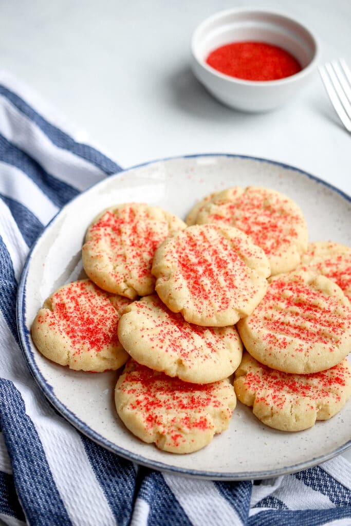 No roll sugar cookies decorated with red sprinkles on a plate.