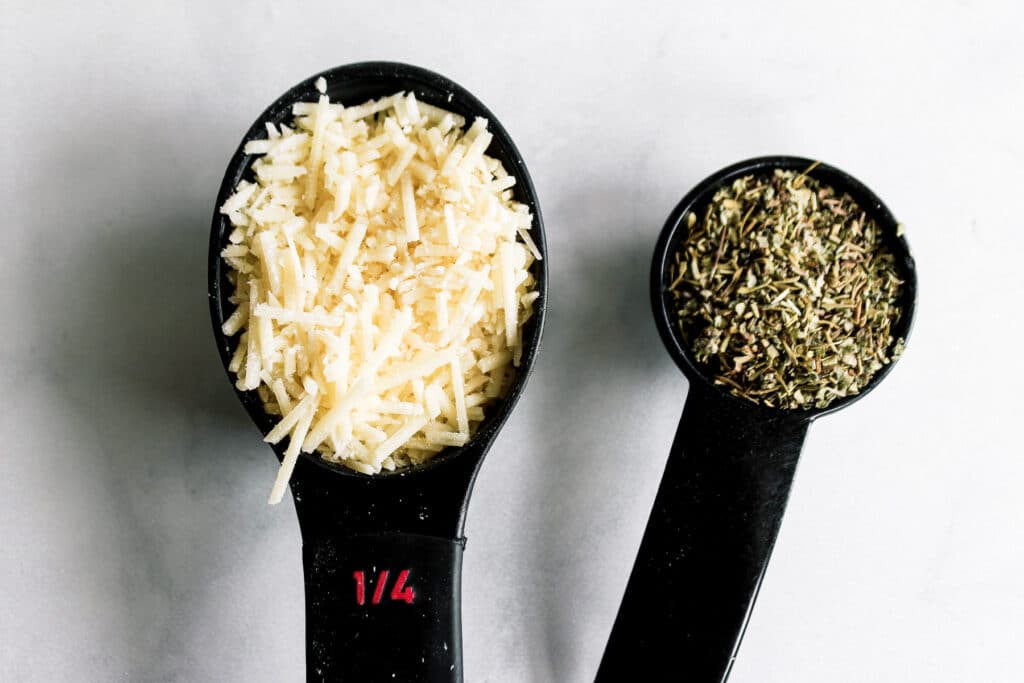 Parmesan cheese and Italian seasoning being measured.