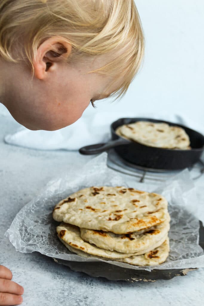 Little one leaning in to look at the flatbreads.