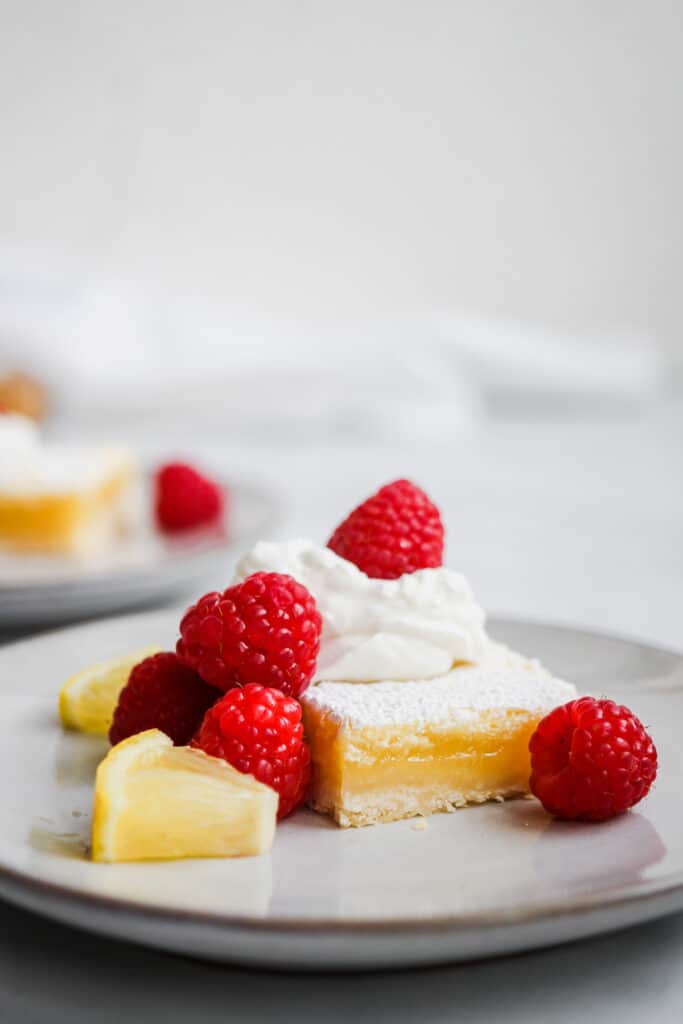 Sliced lemon bar with fresh raspberries.