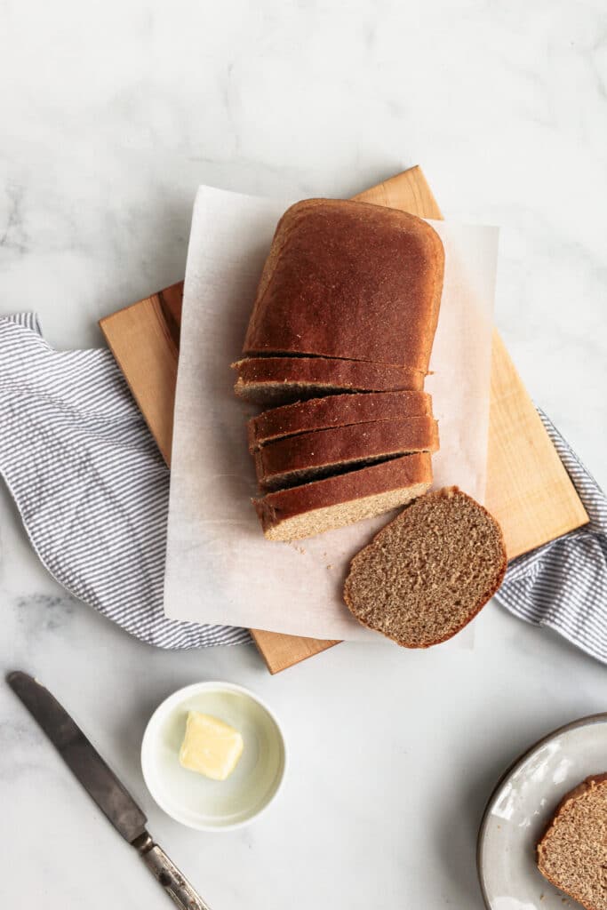 Loaf of bread sliced with a dish of butter and knife.