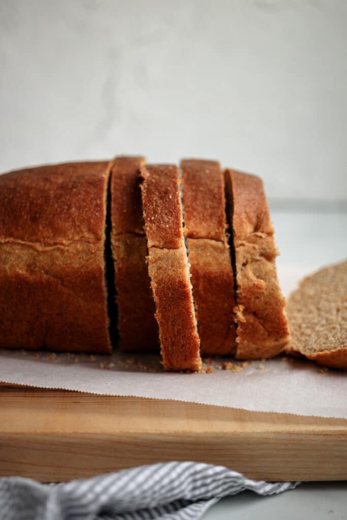 Honey whole wheat bread loaf sliced shown from the side.