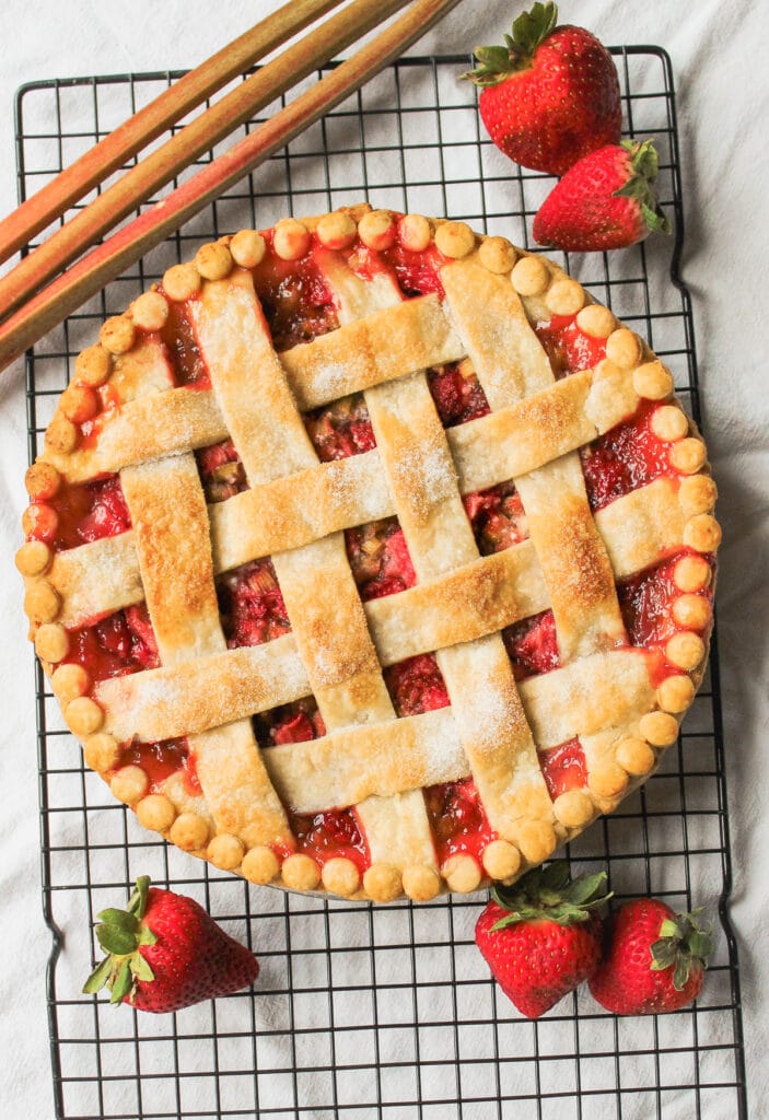 Baked strawberry rhubarb pie with tapioca on a cooling rack.