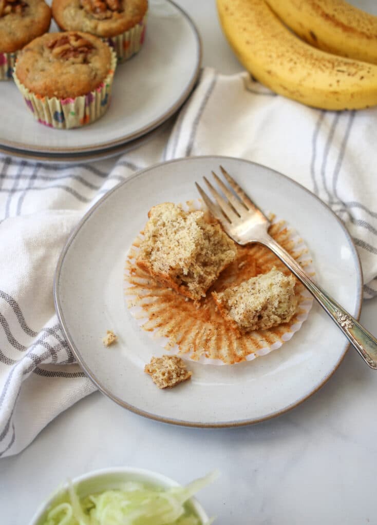 Close up of the banana zucchini muffins on a plate with extra bananas. 